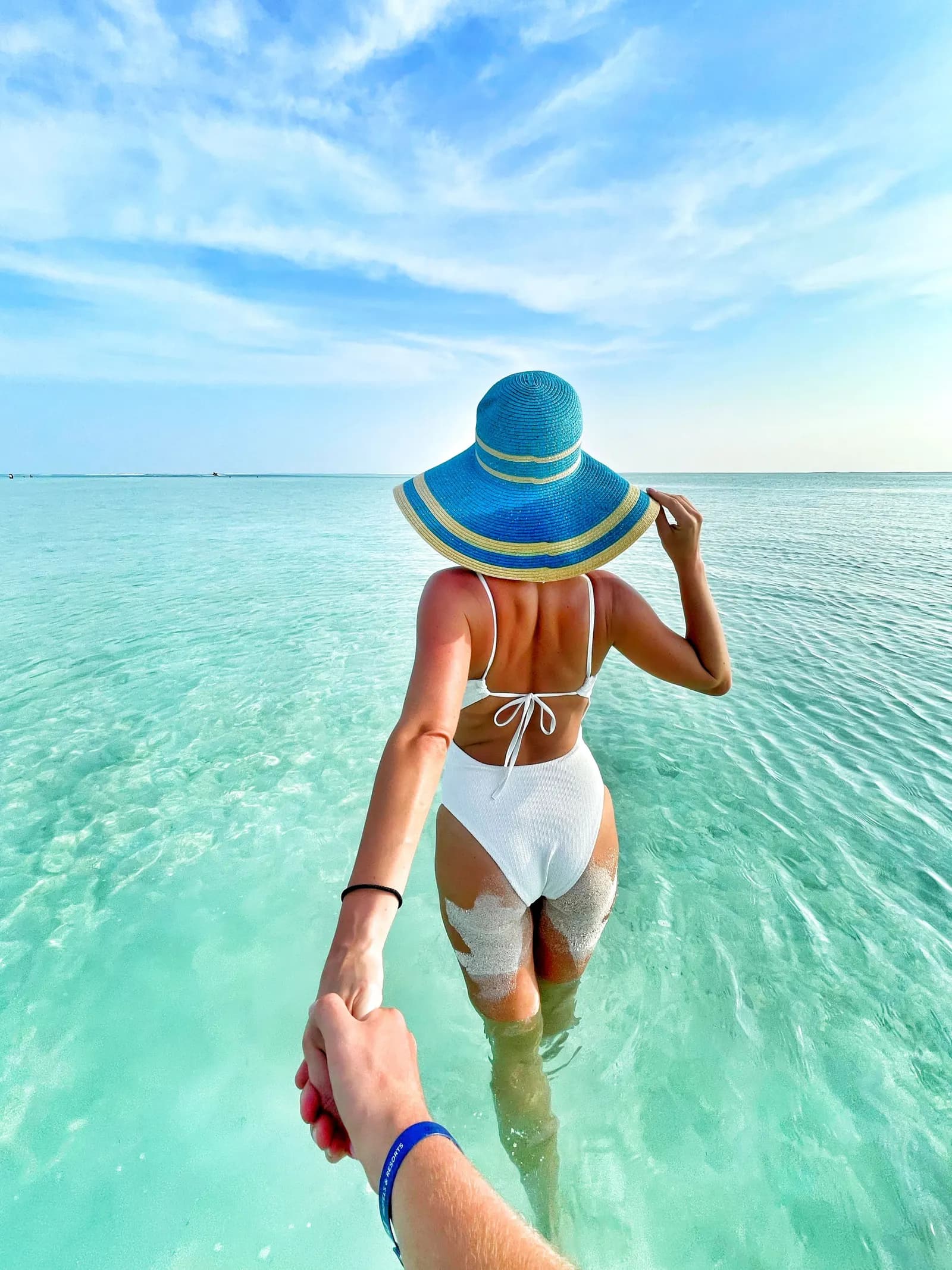 Viajera caminando de la mano sobre aguas turquesa de Isla Mujeres